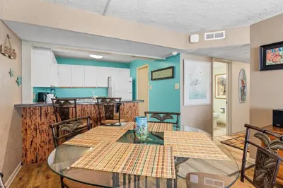 a dining room with a glass table and a kitchen at Pelican Walk 1009 in Panama City Beach