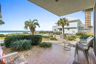 a patio with a view of the beach and palm trees at Pelican Walk 110 in Panama City Beach