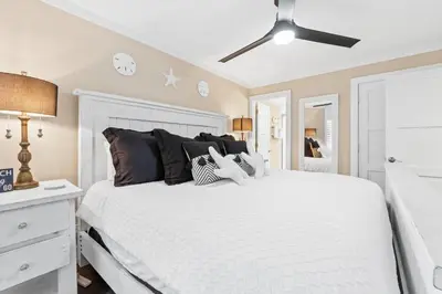 a bedroom with a large white bed with black pillows at Pelican Walk 302 in Panama City Beach