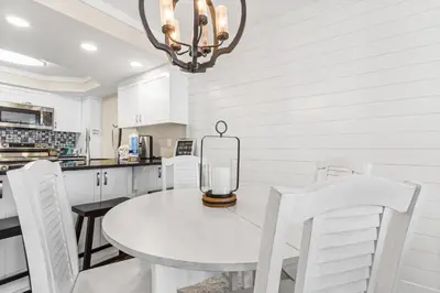a white kitchen with a table and white chairs at Pelican Walk 302 in Panama City Beach