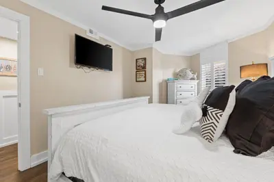 a bedroom with a white bed and a flat screen tv at Pelican Walk 302 in Panama City Beach