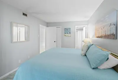 a bedroom with a blue bed in a white room at Pelican Walk 509 in Panama City Beach