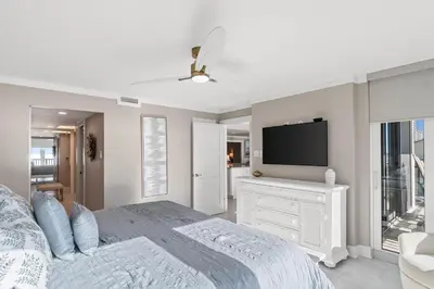 a white bedroom with a bed and a tv at Pelican Walk 405 in Panama City Beach