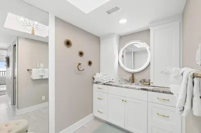 a white bathroom with a sink and a mirror at Pelican Walk 405 in Panama City Beach