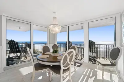 a dining room with a table and chairs and the ocean at Pelican Walk 405 in Panama City Beach