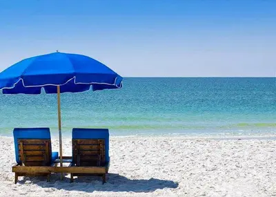 two chairs under an umbrella on a beach at Pelican Walk 610 in Panama City Beach