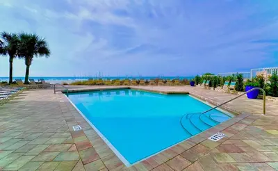 a large blue swimming pool with a view of the ocean at Pelican Walk 610 in Panama City Beach