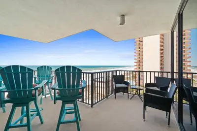 a balcony with chairs and tables and a view of the ocean at Pelican Walk 812 in Panama City Beach
