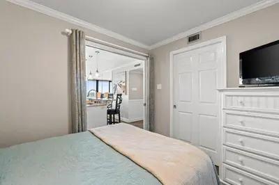 a bedroom with a bed and a dresser with a television at Pelican Walk 104 in Panama City Beach