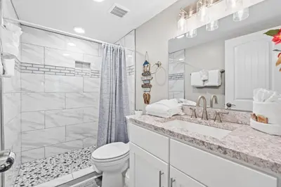 a white bathroom with a toilet and a sink at Pelican Walk 703 in Panama City Beach