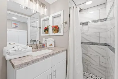 a white bathroom with a shower and a sink at Pelican Walk 703 in Panama City Beach
