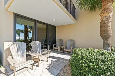 a patio with three chairs and a palm tree at Pelican Walk 111 in Panama City Beach