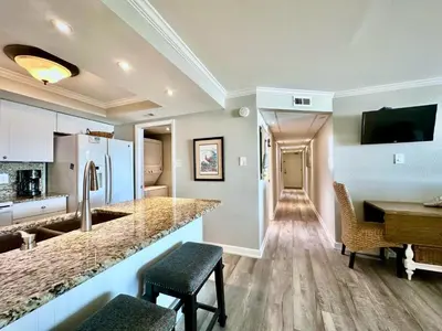 a kitchen and living room with a counter and a table at Pelican Walk 111 in Panama City Beach