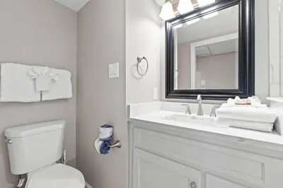 a bathroom with a sink and a toilet and a mirror at Pelican Walk 111 in Panama City Beach