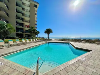 a swimming pool with chairs and a building at Pelican Walk 111 in Panama City Beach