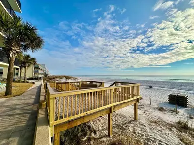 a wooden walkway to the beach with a palm tree at Pelican Walk 111 in Panama City Beach