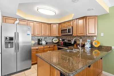 a kitchen with wooden cabinets and a stainless steel refrigerator at Pelican Walk 802 in Panama City Beach