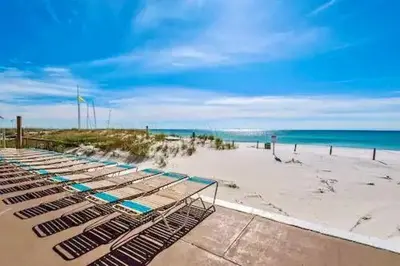 a beach with several lounge chairs on the sand at Pelican Walk 706 in Panama City Beach
