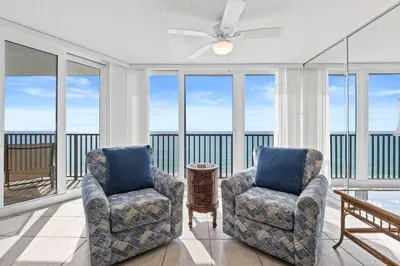 a living room with two chairs and a balcony at Pelican Walk 806 in Panama City Beach