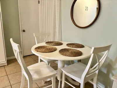 a white table with four chairs and a mirror at Cozy Beach Condo in Complex in Panama City Beach