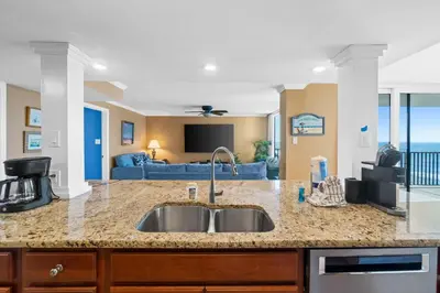 a kitchen with a sink and a living room at Pelican Walk 801 in Panama City Beach