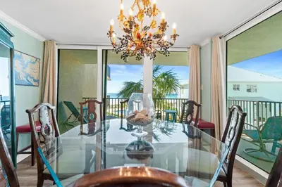 a dining room with a glass table and a chandelier at Pelican Walk 212 in Panama City Beach