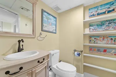 a bathroom with a toilet and a sink and a mirror at Pelican Walk 212 in Panama City Beach