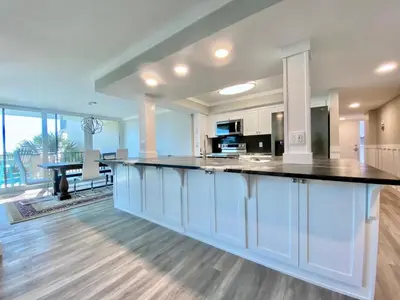 a large kitchen with white cabinets and a black counter top at Pelican Walk 301 in Panama City Beach