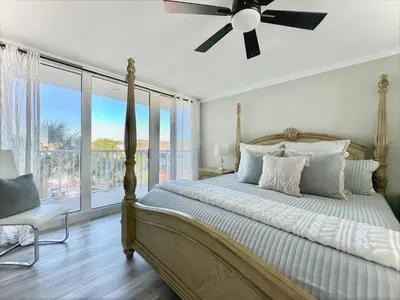 a bedroom with a bed with a ceiling fan and a window at Pelican Walk 301 in Panama City Beach