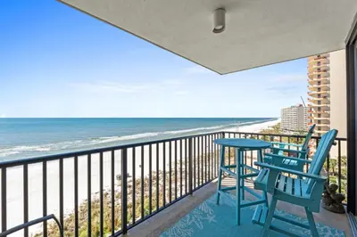 a balcony with two chairs and a table and the ocean at Pelican Walk 810 in Panama City Beach