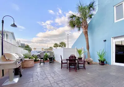 a patio with a table and chairs and a palm tree at Pelican Walk 810 in Panama City Beach