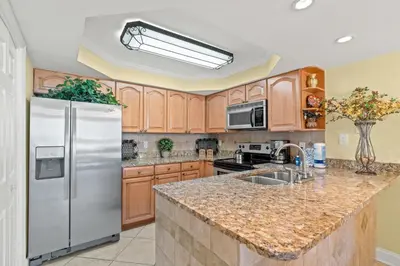 a kitchen with wooden cabinets and a stainless steel refrigerator at Pelican Walk 103 in Panama City Beach