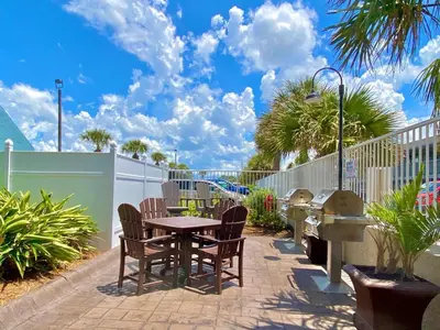 a patio with a table and chairs and a fence at Pelican Walk 103 in Panama City Beach