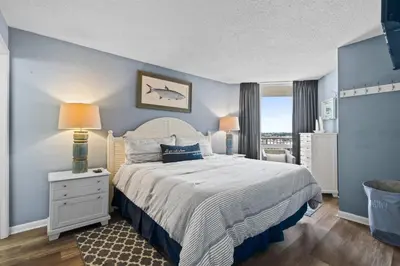 a bedroom with a large bed with a blue wall at Pelican Walk 911 in Panama City Beach