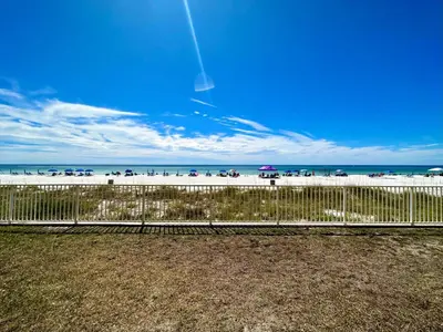 a fence on a beach with people on the beach at Gulfgate 102 in Panama City Beach