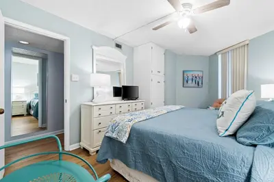 a bedroom with a bed and a dresser with a mirror at Pelican Walk 704 in Panama City Beach