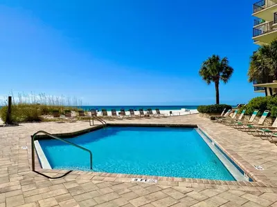 a swimming pool with chairs and the beach at Pelican Walk 704 in Panama City Beach