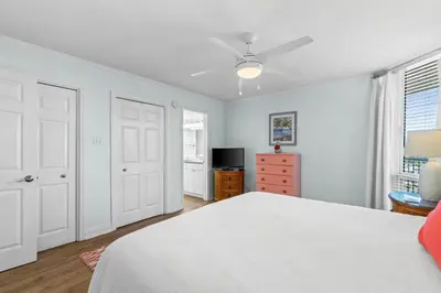 a bedroom with a white bed and a ceiling fan at Pelican Walk 1008 in Panama City Beach