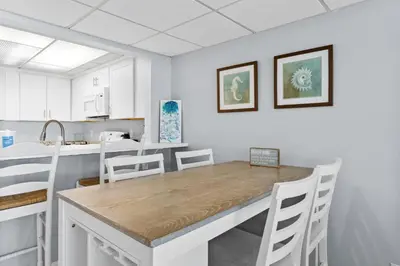 a kitchen with a wooden table and white cabinets at Pelican Walk 804 in Panama City Beach