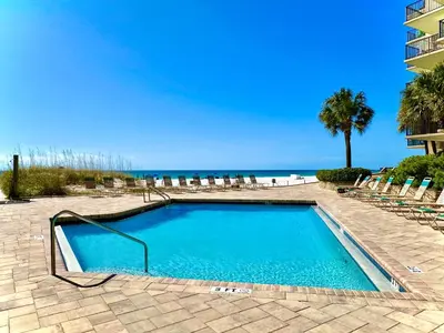 a swimming pool with chairs and the beach at Pelican Walk 804 in Panama City Beach