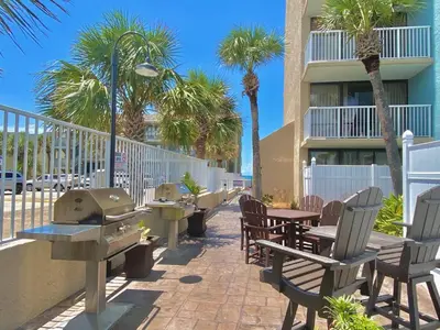 a patio with tables and chairs and palm trees at Pelican Walk 804 in Panama City Beach