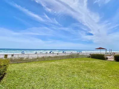 a yard with a fence and the beach with an umbrella at Gulfgate 107 in Panama City Beach