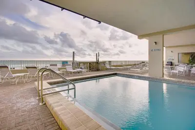 a swimming pool with tables and chairs and the ocean at Gulfgate 107 in Panama City Beach