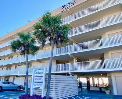 a hotel with palm trees and a sign in a parking lot at Gulfgate 107 in Panama City Beach