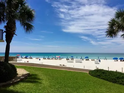 a beach with chairs and umbrellas and the ocean at Pelican Walk 1006/1007 in Panama City Beach