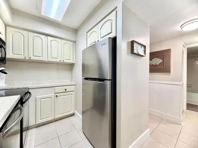 a kitchen with white cabinets and a stainless steel refrigerator at Gulfgate 204 in Panama City Beach