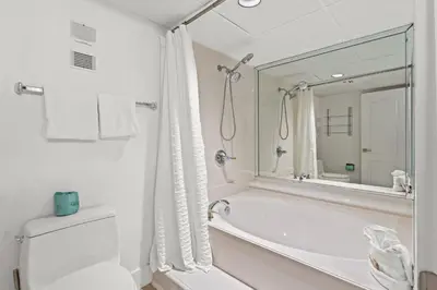 a bathroom with a tub and a toilet and a mirror at Pelican Walk 207 in Panama City Beach