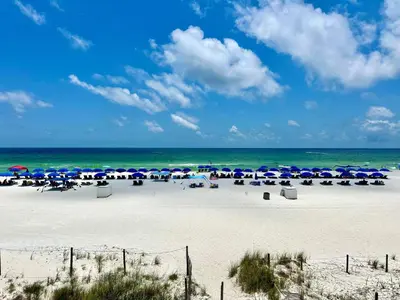 a beach with chairs and umbrellas and the ocean at Pelican Walk 206 in Panama City Beach