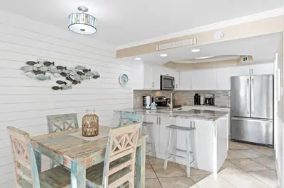a kitchen with a table and a refrigerator at Pelican Walk 510 in Panama City Beach
