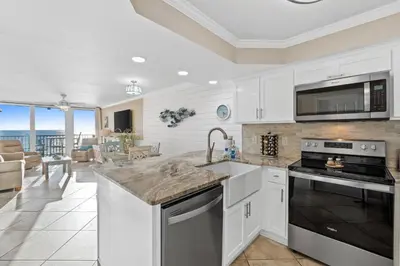 a kitchen with white cabinets and appliances and a living room at Pelican Walk 510 in Panama City Beach